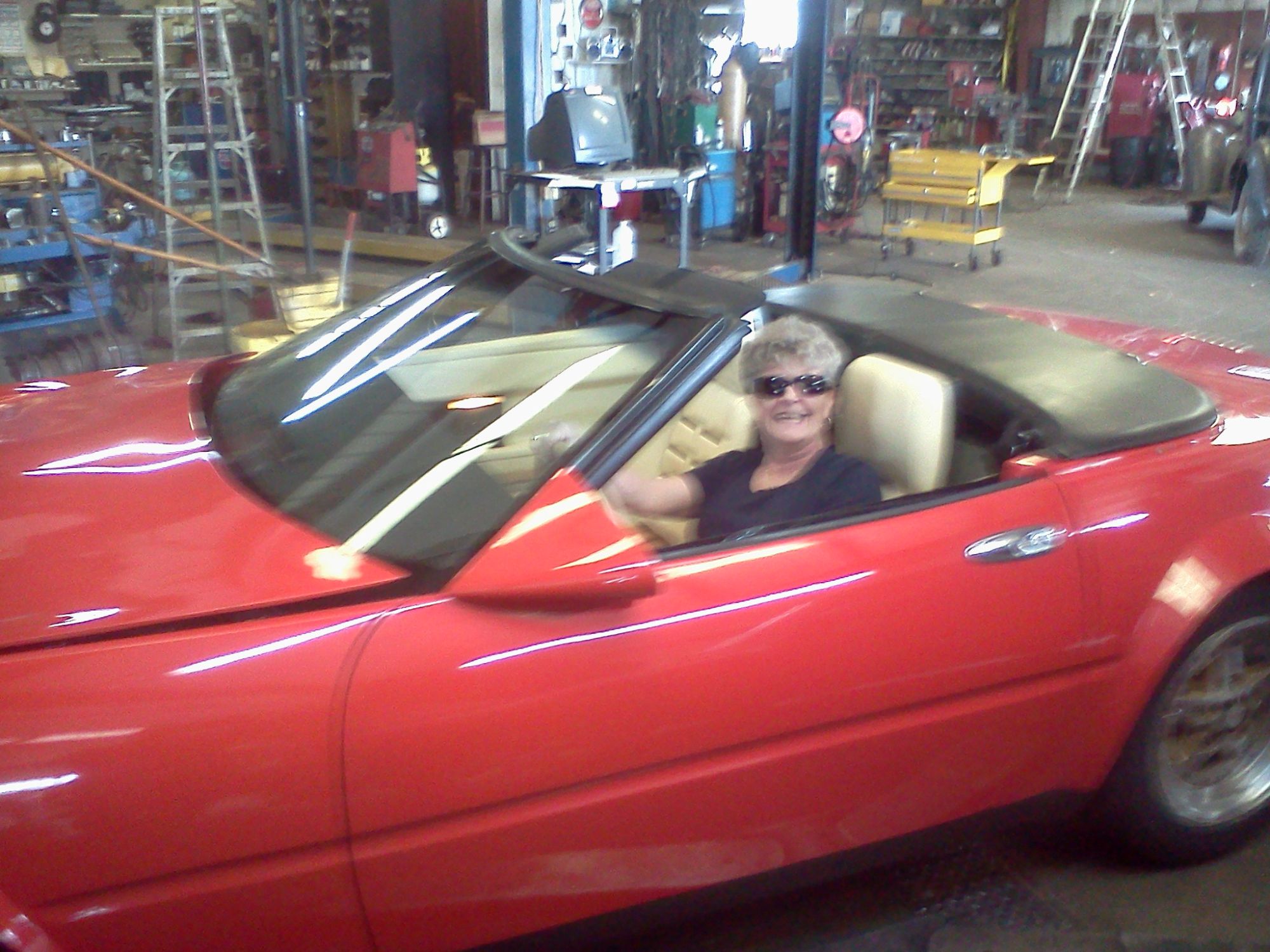 A happy customer in a red convertible at the shop